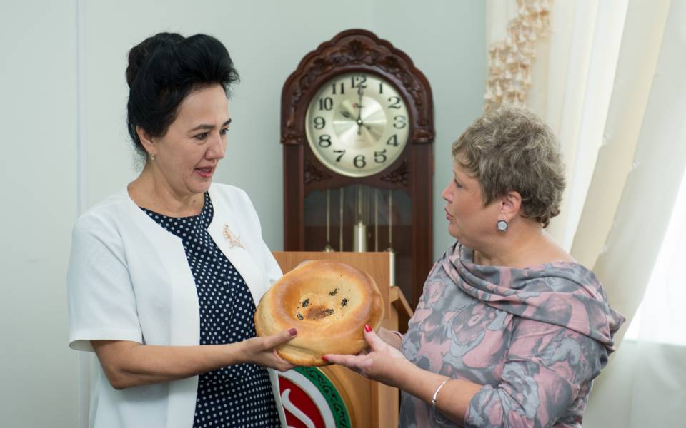 Дилбар Асланова передает узбекскую лепешку Эльвире Садыковой